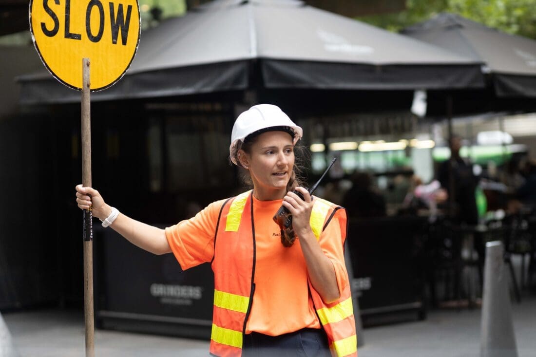 Labour hire brisbane | Fast Labour Hire A construction worker holds a "SLOW" sign and uses a walkie-talkie